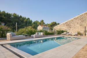 a swimming pool with lounge chairs and a stone wall at Renaissance Palace Ghetaldi 1516 in Suđurađ