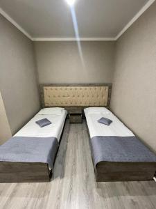 two beds in a small room with a light at VIP Mini Hotel in Semey