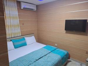 1 dormitorio con 1 cama y TV de pantalla plana en Haffy Executive Hotels and Suite en Uyo