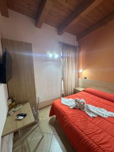 a bedroom with a red bed with a table and a television at MANDANICI :Borgo Marsalini 2.0 in Barcellona-Pozzo di Gotto