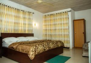 1 dormitorio con 1 cama grande y cortinas en Haffy Executive Hotels and Suite en Uyo