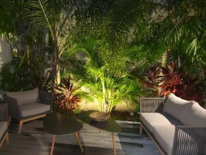 un patio con sofás, una mesa y plantas en Le Rocher Vert - Duplex climatisé pour 4, en Saint Barthelemy