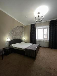 a bedroom with a large bed and a chandelier at VIP Mini Hotel in Semey