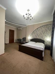 a bedroom with a large bed and a chandelier at VIP Mini Hotel in Semey