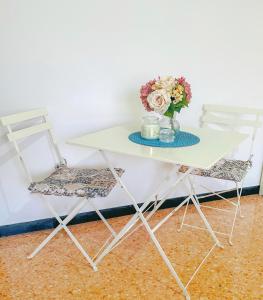 een witte tafel met twee stoelen en een vaas met bloemen bij La casita A&B in La Spezia