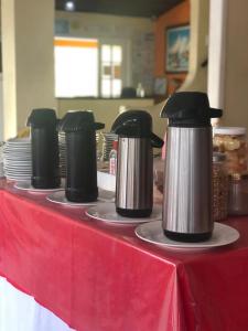 a table with three coffee pots and plates on it at Thetis Hotel Pousada in Arraial do Cabo