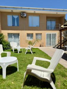 un gruppo di panchine bianche sull'erba di fronte a un edificio di Verona Hostel a Necochea Altre 62 foto