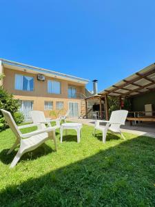 a group of chairs sitting on the grass in front of a house at Verona Hostel in Necochea