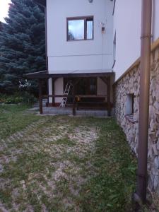a white house with a stone wall and a bench at Alfa 2 apartament 3 in Bystra