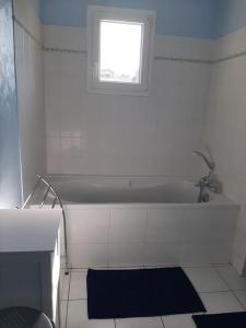 a white bathroom with a tub and a window at Gîte l'Etape in Pirajoux