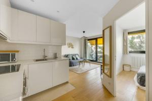 Una cocina con gabinetes blancos y una sala de estar. en Espace Champerret - 1 Bedroom 4 people, en Levallois-Perret