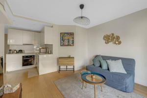 Una sala de estar con un sofá azul y una cocina. en Espace Champerret - 1 Bedroom 4 people, en Levallois-Perret