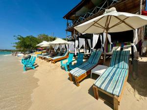 a row of chairs and umbrellas on a beach at Tequila SunBeach Baru Eco-Hotel in Barú