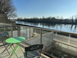 a balcony with a table and chairs and a view of a river at Appartement T3 bord de la Vienne in Chinon