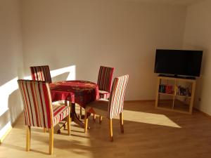 uma mesa de jantar com quatro cadeiras e uma televisão em Fewo Panoramablick em Winterscheiderbröl