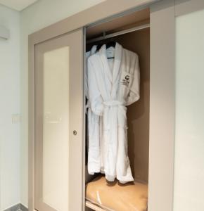 un armario con toallas blancas colgando en él en Vila Gale Collection Figueira da Foz en Figueira da Foz