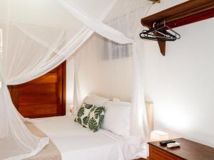 a bedroom with a canopy bed with white curtains at CASA SIMONI Trancoso in Trancoso