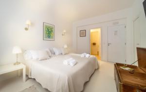 ein weißes Schlafzimmer mit einem Bett mit Handtüchern darauf in der Unterkunft Ca Sa Padrina d'Artà-Turismo de Interior in Artá