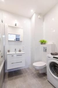 ein weißes Bad mit einem WC und einer Waschmaschine in der Unterkunft Apartament MioMare Letnica Seaside in Danzig