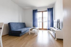 a living room with a blue couch and a tv at Apartament MioMare Letnica Seaside in Gdańsk