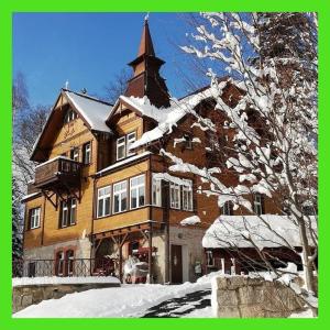 duży drewniany budynek z wieżą w śniegu w obiekcie Willa Nimfa - dla Grup i Gości indywidualnych w Szklarskiej Porębie