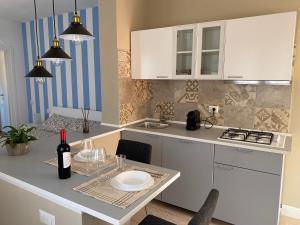 a kitchen with white cabinets and a table with a bottle of wine at La Collina: Il tramonto in Castiadas