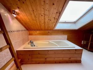 a large bath tub in a room with a skylight at Chalet Le Chappoix, 4* avec grand jardin in Granges-sur-Vologne