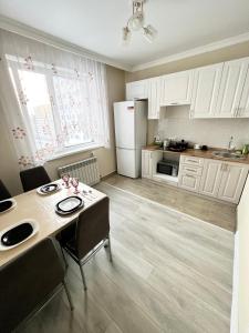 a kitchen with white cabinets and a table with chairs at Жк sezim Qala in Taldykolʼ