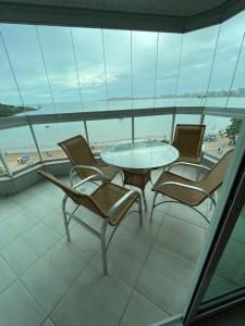 a table and chairs on a balcony with a view of the beach at Apartamento Beira MAr in Guarapari