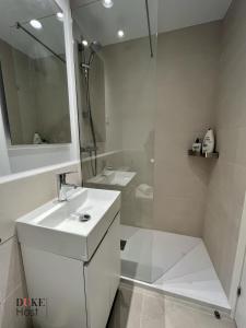 biała łazienka z umywalką i prysznicem w obiekcie Duke Vallehermoso Apartament w Madrycie