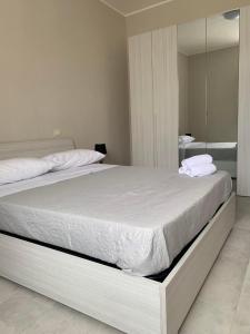 1 dormitorio con 1 cama blanca grande y espejo en B&b stella caltavuturo, en Caltavuturo