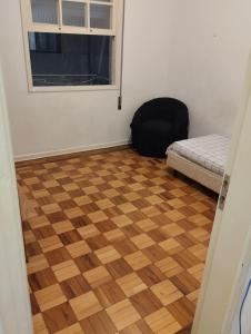 a room with a wooden floor and a window and a bed at Aphostel gatinhos perça caiçara in Santos