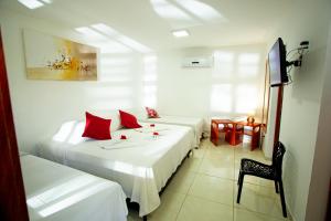 um quarto de hotel com duas camas com almofadas vermelhas em Pousada Villa Caju em Jericoacoara
