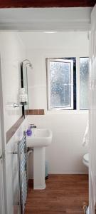 ein weißes Bad mit einem Waschbecken und einem Fenster in der Unterkunft Durham House in Beer