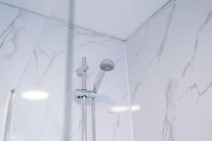 a shower with a shower head in a bathroom at Sleek and Stylish 3 BR Home Mcr in Manchester
