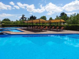 a large swimming pool with chairs and umbrellas at Cabanas Turismo Don Ambrosio in El Manzano