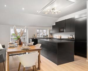 una cocina con armarios negros y una mesa con sillas blancas en Homerentals l 120sqm Mid-central - King beds - 500Mbps WI-FI, en Bergen