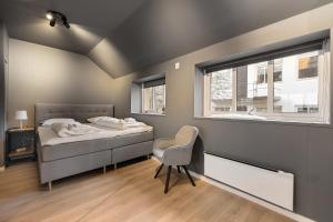 een slaapkamer met een bed, een stoel en een raam bij Homerentals l 120sqm Mid-central - King beds - 500Mbps WI-FI in Bergen