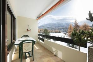 a balcony with a table and a view of the mountains at Modern crossing apartment facing Piz Rosatsch in St. Moritz