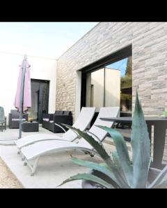 un gruppo di sedie bianche e un tavolo su un patio di Villa Chêne Vert Wifi Clim Parking privé a Les Angles Gard