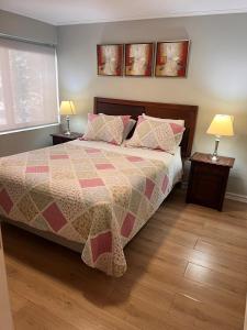 1 Schlafzimmer mit einem Bett mit einer Decke und 2 Lampen in der Unterkunft Isabel Suites Vitacura in Santiago