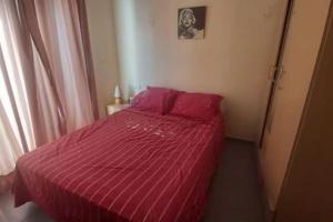 a bedroom with a red bed with a red comforter at Holikeys - Agadir - 2 Ch - El Houda 001 in Agadir
