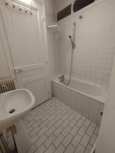 a white bathroom with a sink and a bath tub at Chambre spacieuse - Trocadéro in Paris