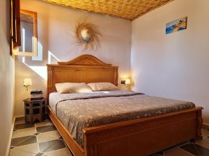 een slaapkamer met een bed met een houten hoofdeinde bij Surf hostel Morocco in Tamraght Ouzdar