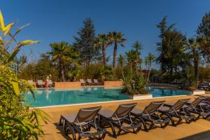 - une rangée de chaises en face d'une piscine dans l'établissement Domaine La Pinède Enchantée, à Argelès-sur-Mer