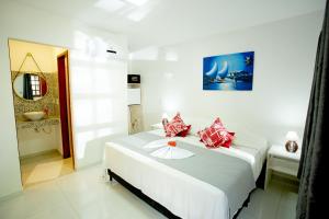 a white bedroom with a bed with red pillows at Pousada Villa Caju in Jericoacoara