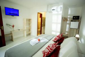 a bedroom with a large bed with red and white pillows at Pousada Villa Caju in Jericoacoara