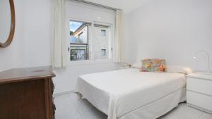 a white bedroom with a bed and a window at 1Pand02 in Llafranc