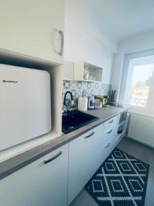 a kitchen with white cabinets and a sink and a window at AVA PROPERTY RENTALS in Făgăraş