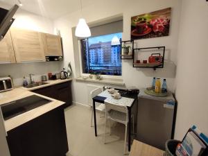 a kitchen with a small table and a kitchen with a window at Apartament Gardena Olsztyn Jaroty in Olsztyn
